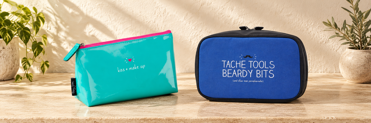 Turquoise Kiss and Make Up makeup bag and blue Tache Tools Beardy Bits wash bag on a stone surface.