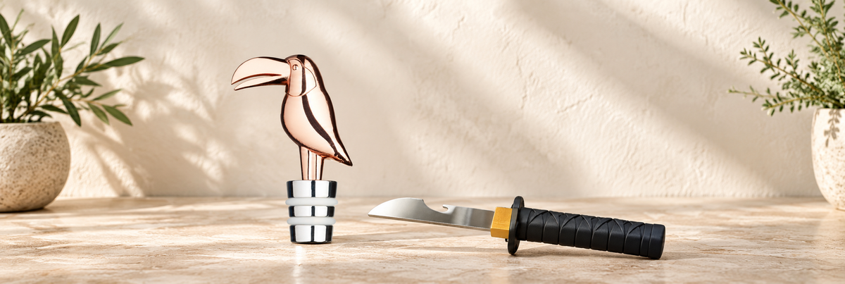 Toucan Bottle Stopper and Bottle Ninja Bottle Opener arranged in a warm, softly lit setting.