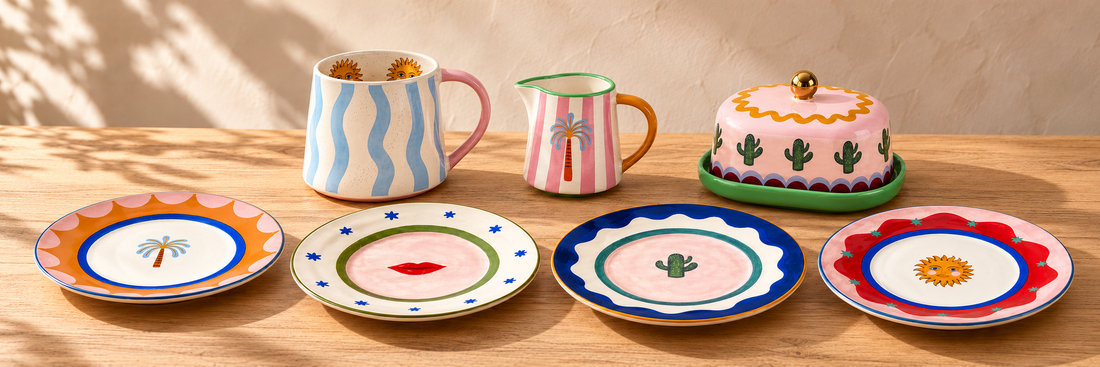 Eleanor Bowmer Electric Coast blue wave mug, palm milk jug, cactus butter dish and four illustrated cake plates on a sunlit oak table