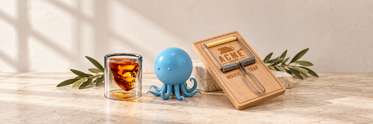 Skull shot glass, blue octopus tea infuser and wooden cheese slicer on a table