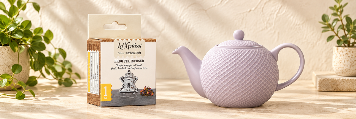 Le'Xpress Frog Tea Infuser and Globe Textured Teapot - Lilac, 4-Cup arranged in a warm, softly lit setting.