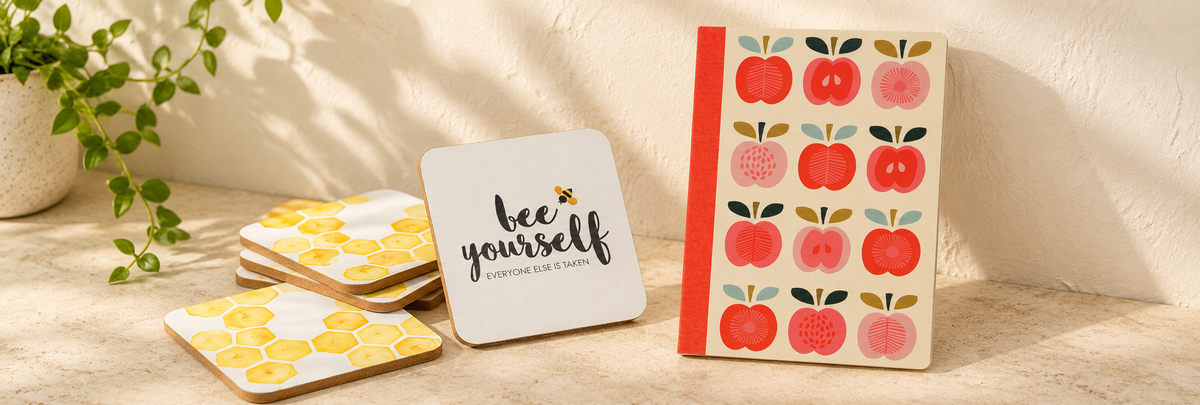OTT Bee Yourself Pack Of 4 Coasters and Vintage Apple A6 Notebook arranged in a warm, softly lit setting.