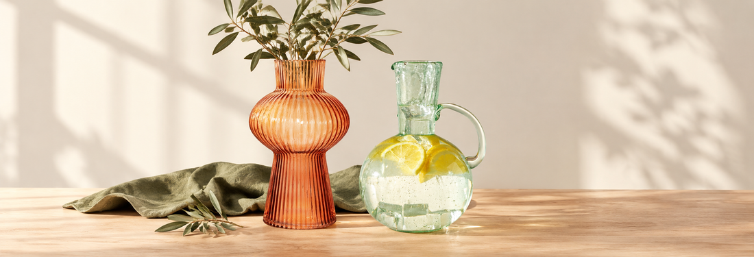 Amber ribbed glass vase beside a recycled glass jug filled with lemon water