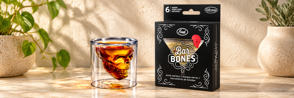 Doomed Skull Shot Glass and Bar Bones Skull Drink Markers arranged in a warm, softly lit setting.