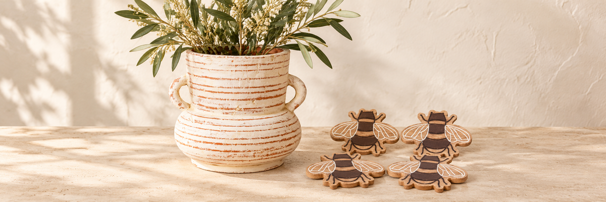Daphne Amphora Vase - Whitewashed Terracotta and Mango Wood Bee Coasters - Set of 4 arranged in a warm, softly lit setting.