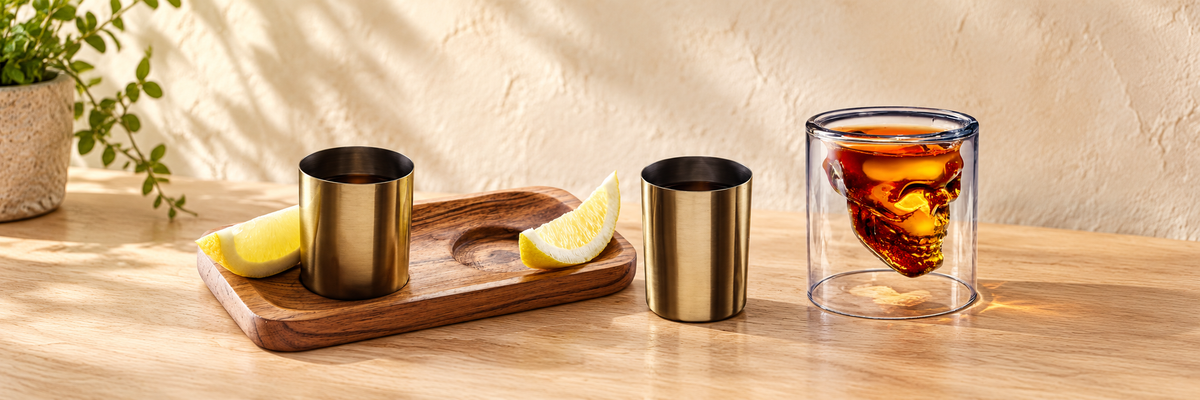 Doomed Skull Shot Glass and Brass-Finish Shot Glass Gift Set - 3 Pieces arranged in a warm, softly lit setting.