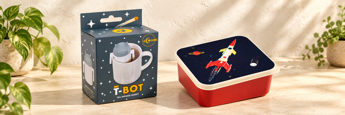 Cosmos - T-Bot Robot Tea Infuser and Space Age Lunch Box arranged in a warm, softly lit setting.
