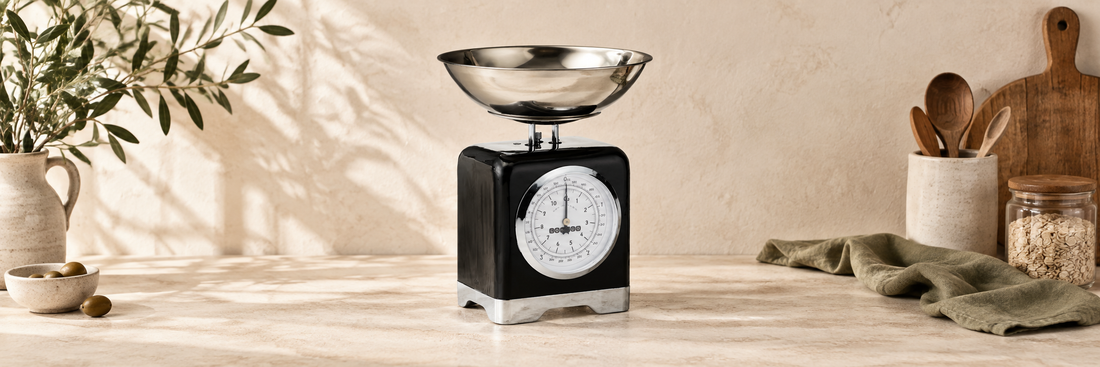Black mechanical kitchen scales with a stainless steel weighing bowl