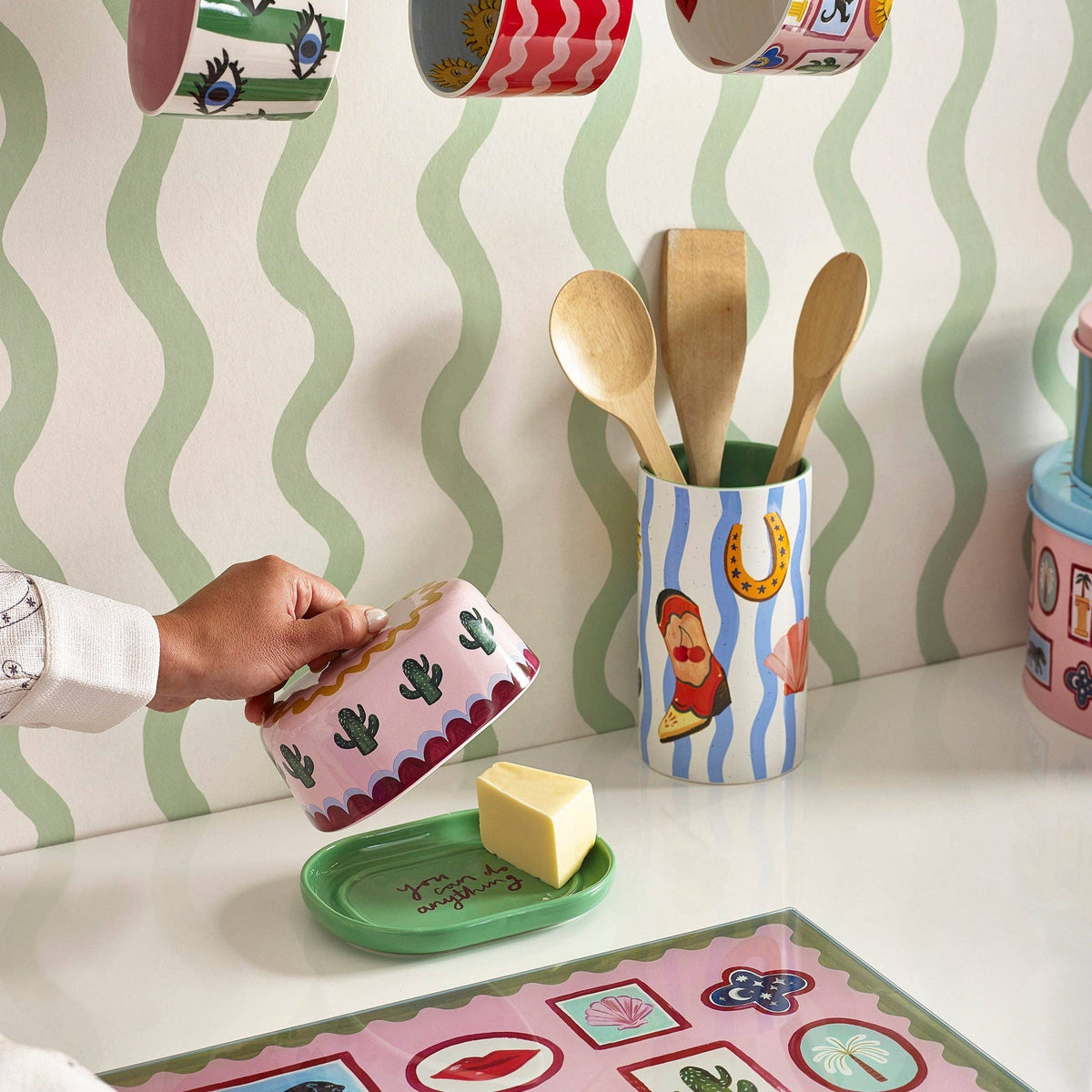 Person lifting the pink cactus butter dish lid in a styled kitchen